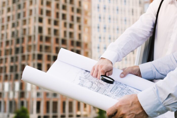 Architects examining building blueprint outdoors